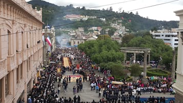 A crowded street with a large gathering of people, a monument, and buildings in the background.