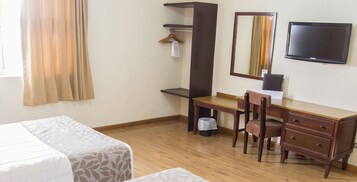 Una habitación de hotel con cama, escritorio, silla, televisor y armario.