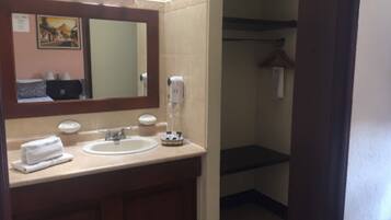 A bathroom with a sink, mirror, towel, and hand dryer.