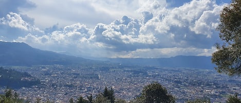 Ein weitreichender Blick auf eine Stadt mit Bergen im Hintergrund und einem dicht bebauten Stadtgebiet im Vordergrund.
