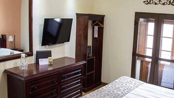 A bedroom with a bed, a dresser, a television, and a wardrobe.