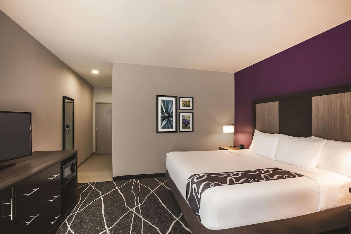 A hotel room with a bed, a TV, a desk, and a chair.