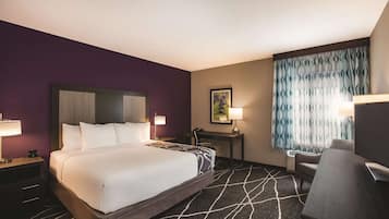 A hotel room with a large bed, a desk, a chair, and a television.