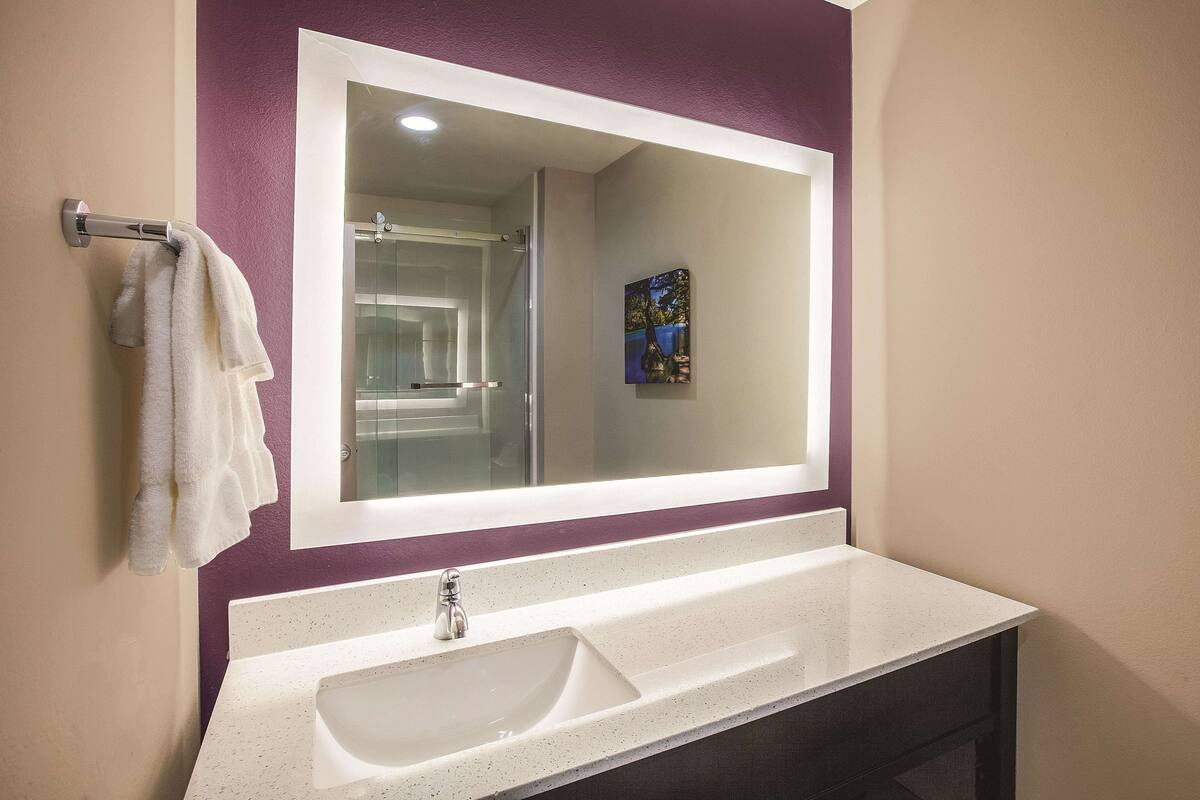 A bathroom with a white sink, a large mirror, and a towel rack.