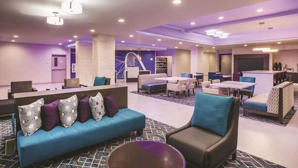 Un moderno vestíbulo de hotel con áreas de descanso, un mostrador de recepción y una escalera.