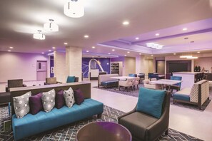 Un moderno vestíbulo de hotel con áreas de descanso, un mostrador de recepción y una escalera.