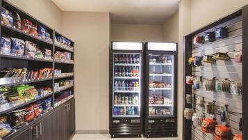Un área autoservicio de refrigerios y bebidas, con dispensadores refrigerados y estantes llenos de diversas opciones de comida y bebida.