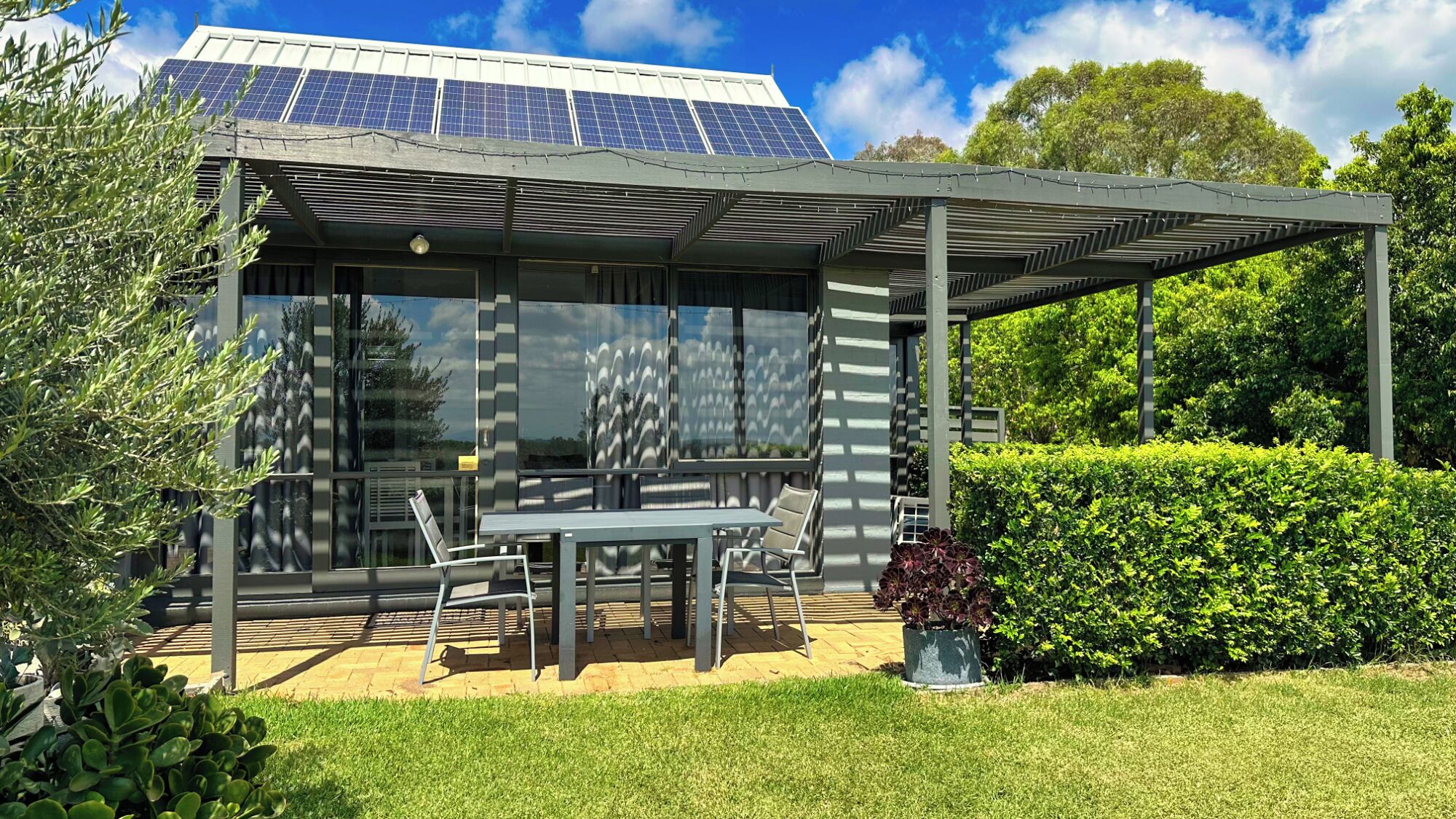 Un edificio moderno con amplios ventanales y un área de estar exterior techada.