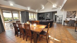 A spacious living area with a dining table, chairs, a sofa, and a TV. - Grapevines Boutique Accommodation (Pokolbin)