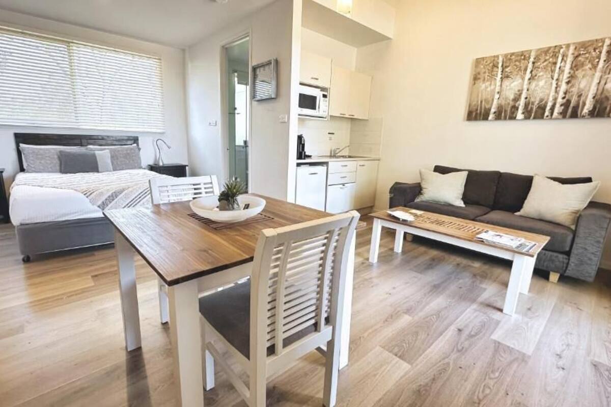 Un dormitorio moderno con una cama grande, mesitas de noche, un escritorio y un sofá.