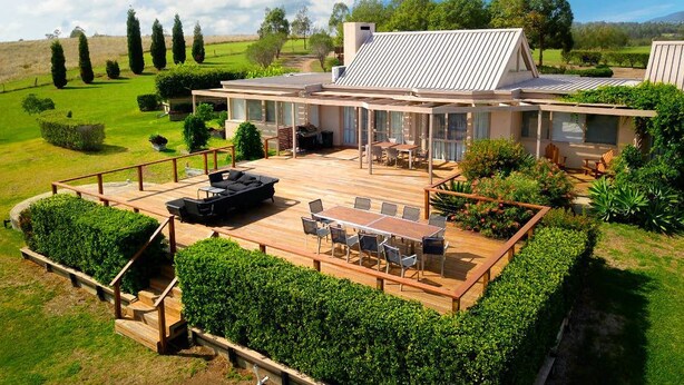 A modern house with a large deck, outdoor furniture, and a well-maintained garden. - Grapevines Boutique Accommodation (Pokolbin)
