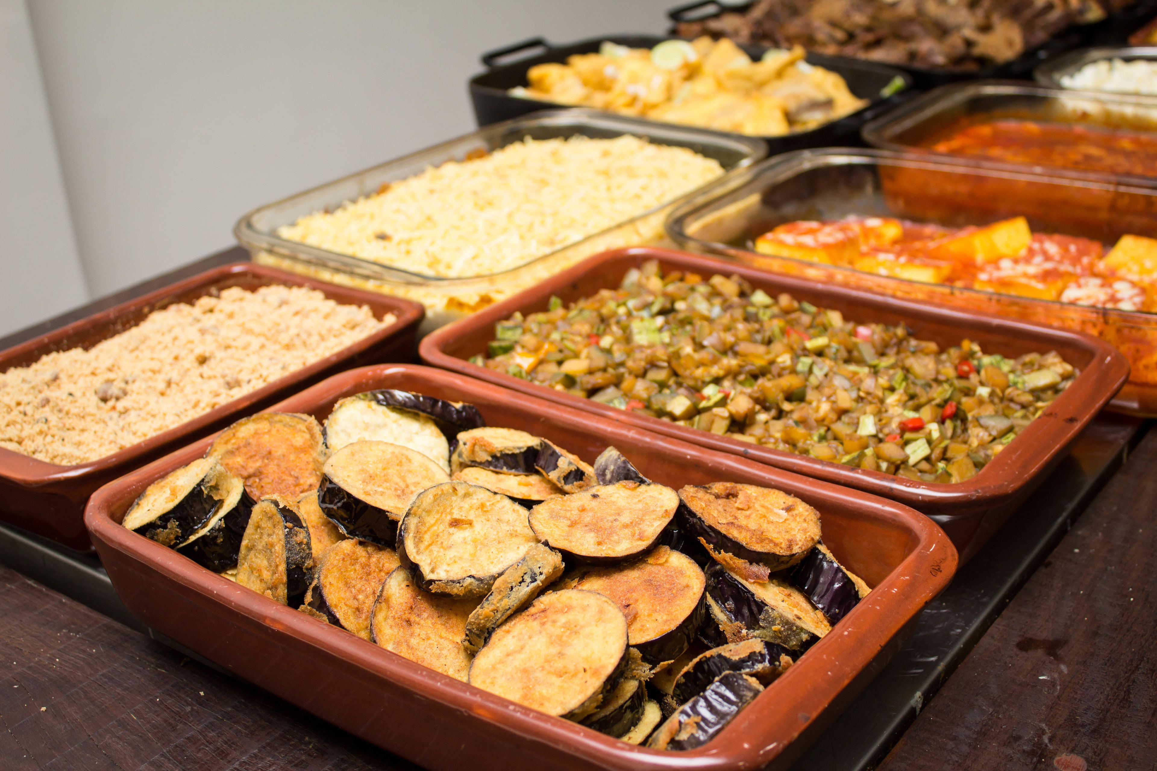 A buffet with various dishes including roasted vegetables and casseroles.