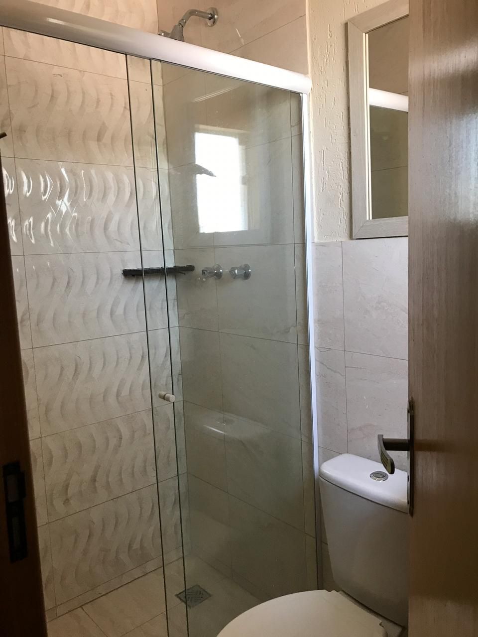 A bathroom with a glass shower enclosure, a toilet, and a sink.