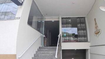 A hotel entrance with a glass door, a staircase, and a signboard.