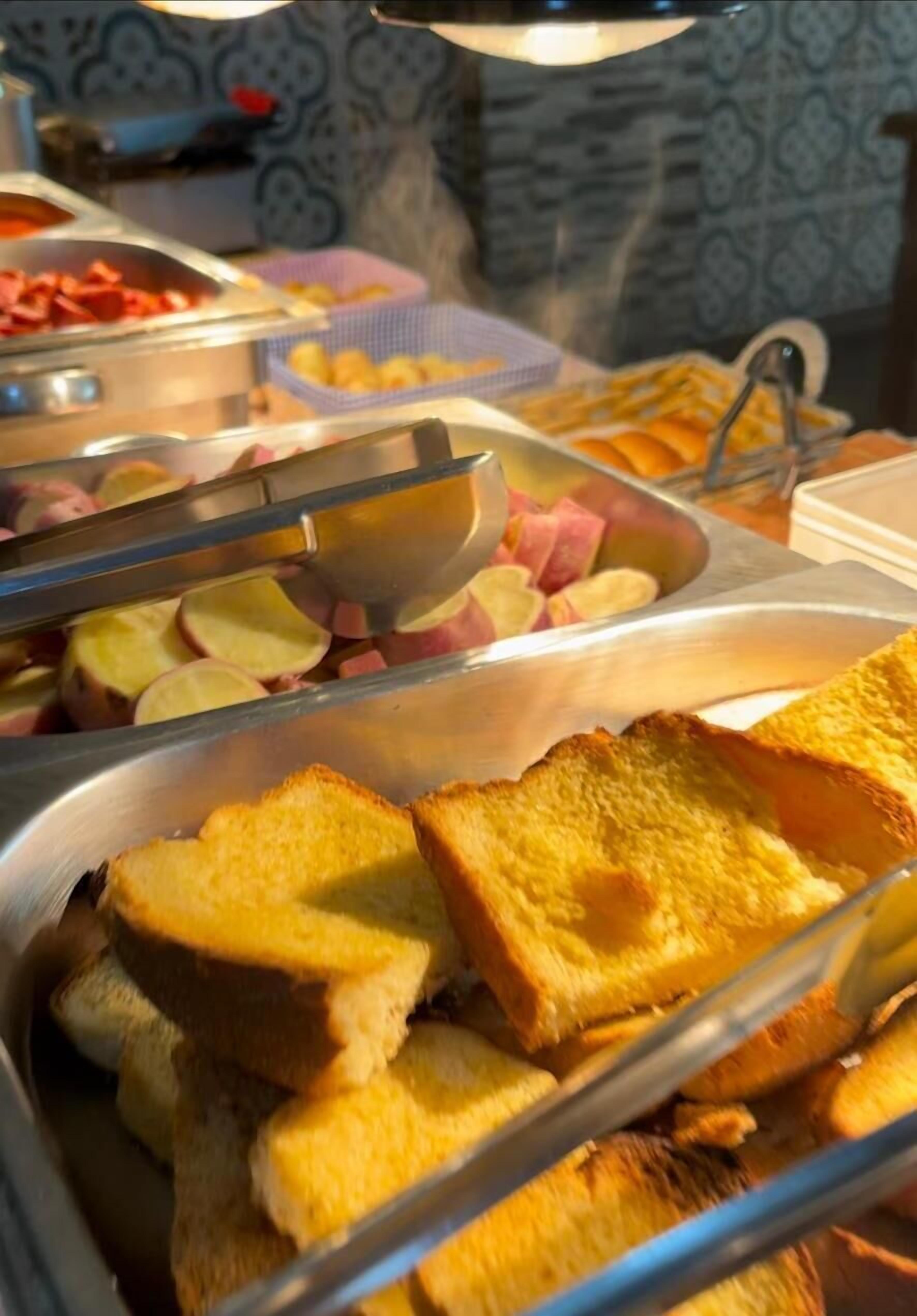 A buffet with various food items including sliced apples, ham, and toast.