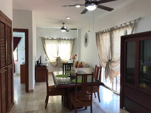 A dining area with a table, chairs, a ceiling fan, and curtains. - Lilas del Mar (Playa del Carmen)