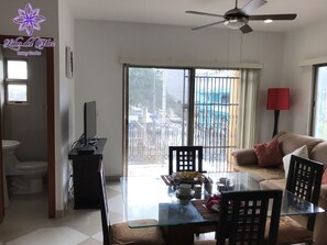 A spacious living area with a glass dining table, a sofa, and a ceiling fan. - Lilas del Mar (Playa del Carmen)