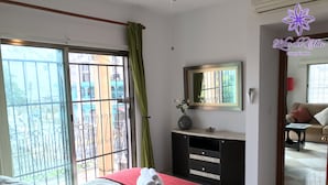 Un dormitorio con cama, cómoda, espejo y vistas a través de un balcón.