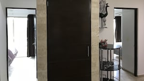 Un interior moderno con una puerta oscura, una columna de mármol, un expositor de vidrio y vistas a otra habitación.