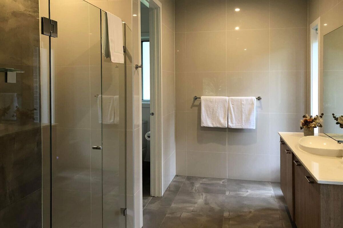 A modern bathroom with a glass shower enclosure, a vanity with a sink, and a towel rack.