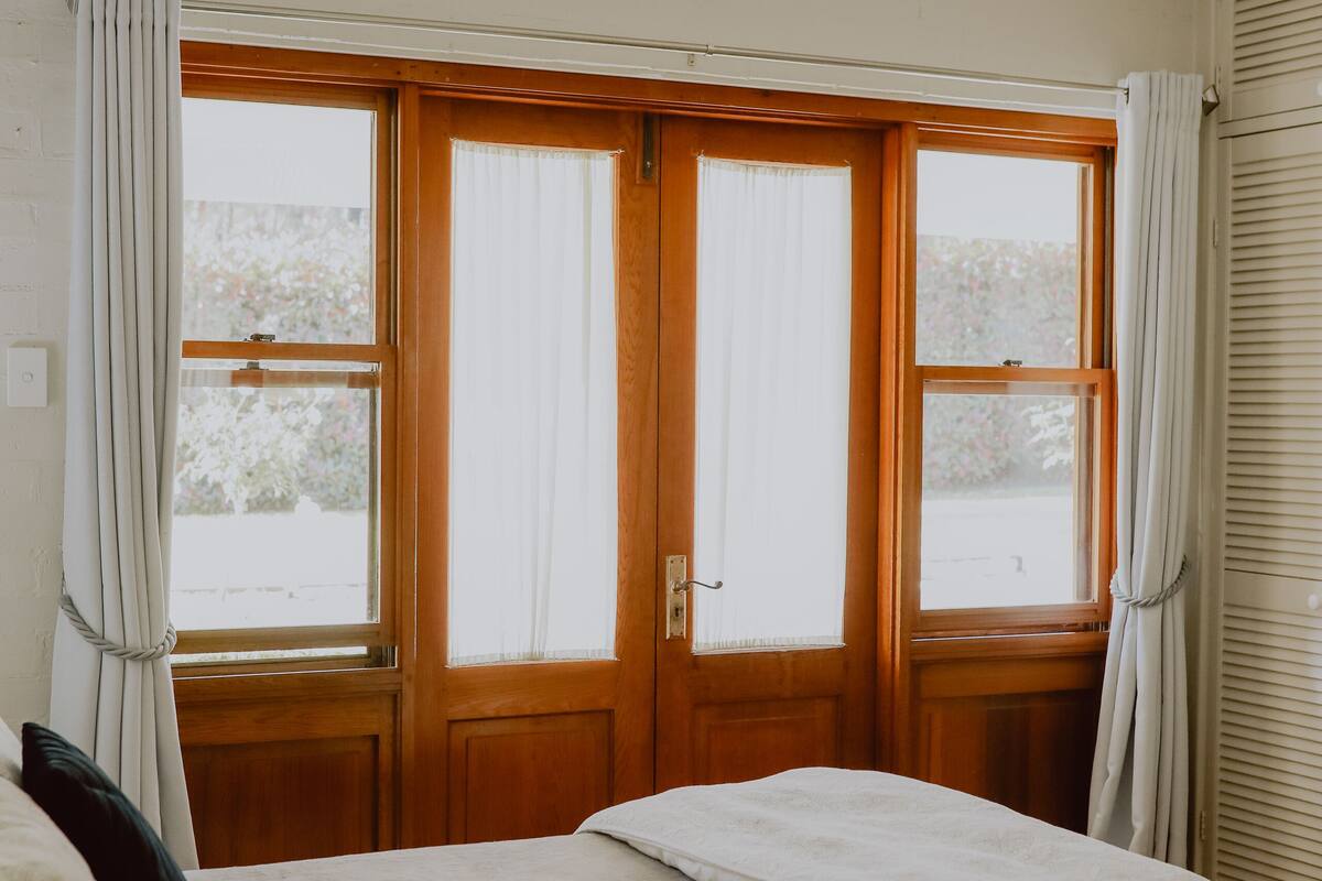 A bedroom with a bed, a ceiling fan, and two windows with curtains.