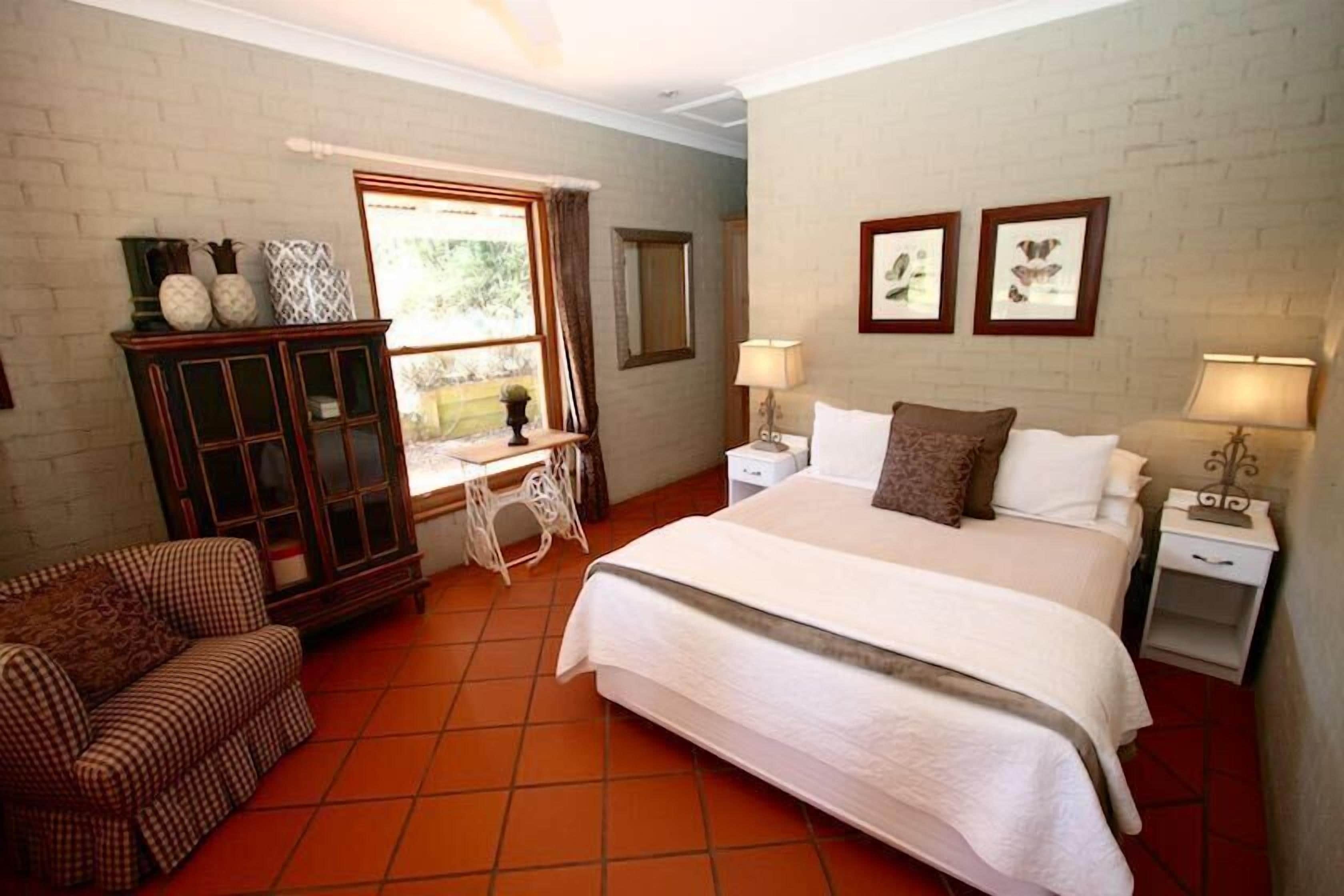 A bedroom with a large bed, a desk, a chair, and a cabinet.