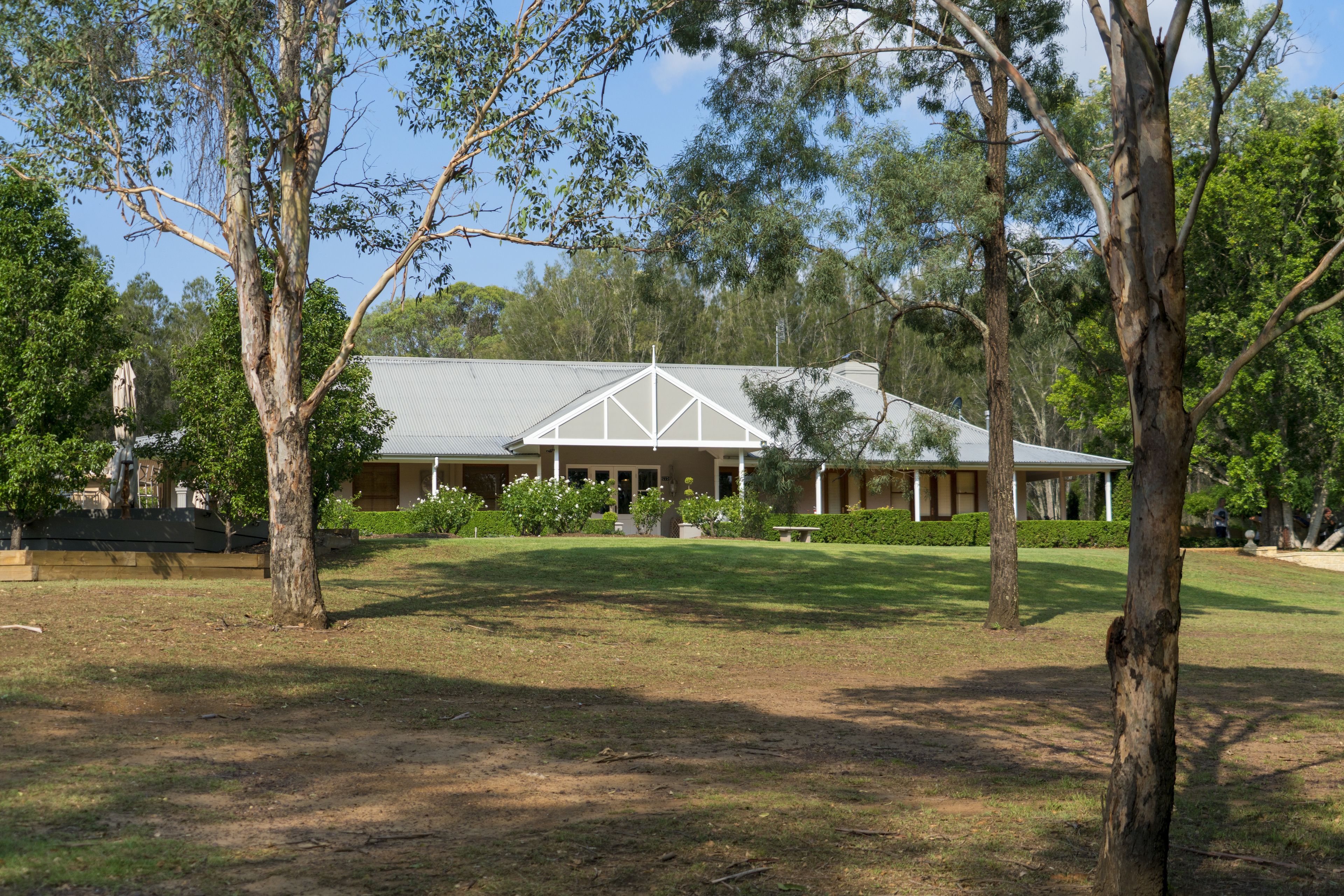 A large, single-story building with a symmetrical facade, surrounded by mature trees and a well-maintained lawn.