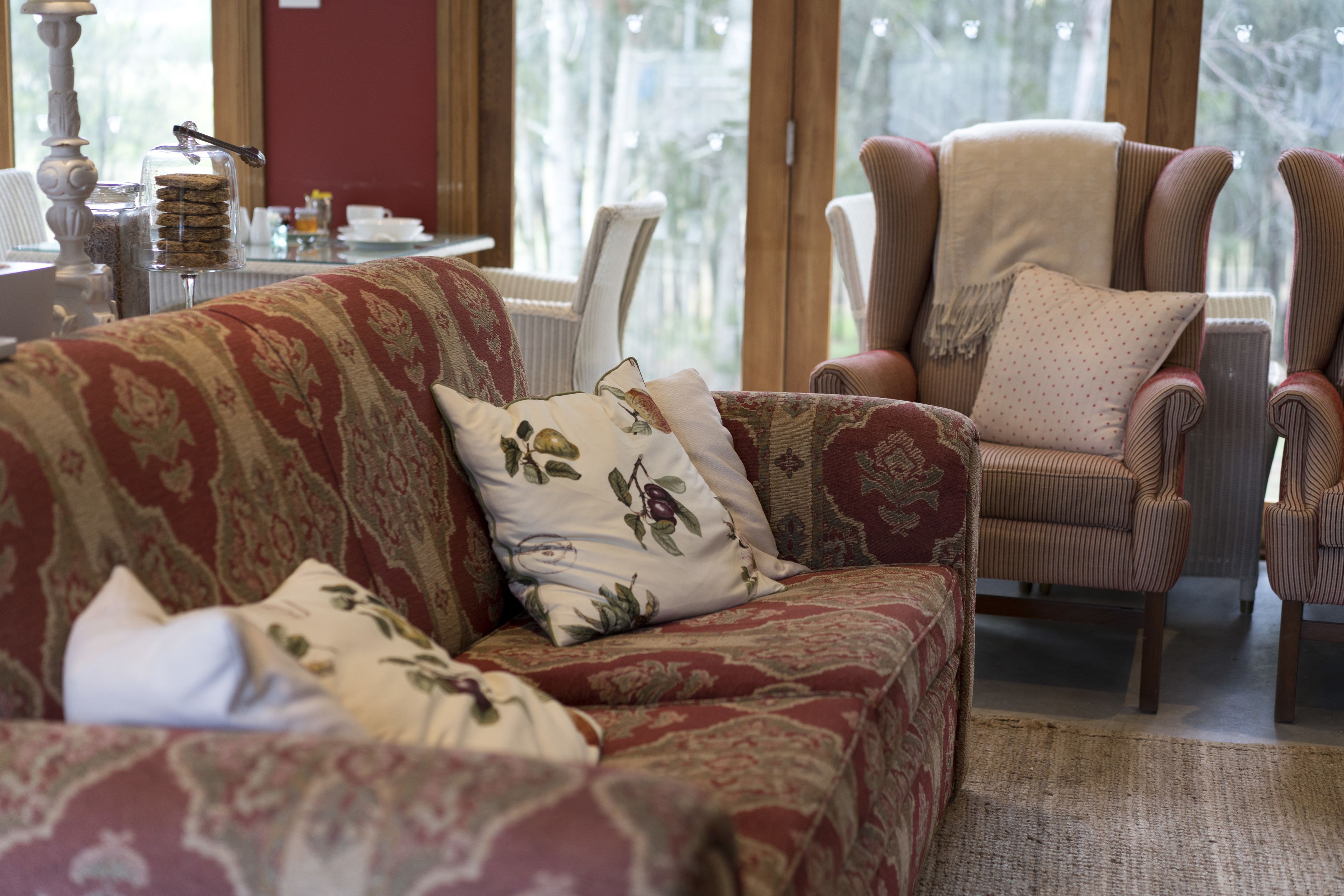 A cozy living room with a patterned sofa, a cushioned armchair, and a side table with a decorative glass container.