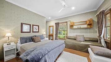 A bedroom with a bed, bedside tables, a ceiling fan, a window with curtains, and a wooden cabinet above the bed.