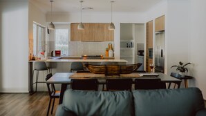 A modern kitchen with a central island, pendant lights, and wooden cabinets. - Thistle Hill Guest House (Pokolbin)