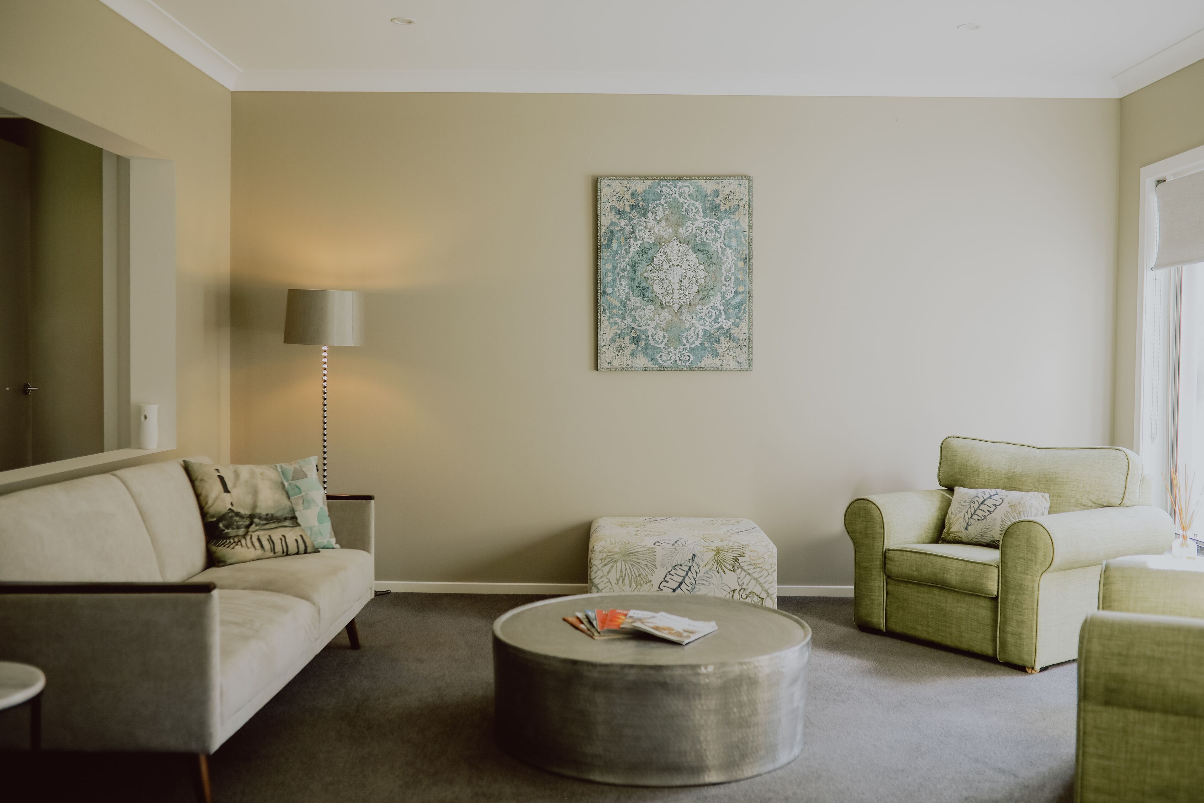 Una sala de estar con sofá, sillón, reposapiés y lámpara.