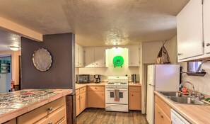 Une cuisine compacte équipée d’un four à micro-ondes, d’un grille-pain, d’une cuisinière et d’un évier.