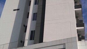 Ein modernes Hochhaus mit symmetrischer Fassade, mehreren Balkonen und einem verschlossenen Eingang.