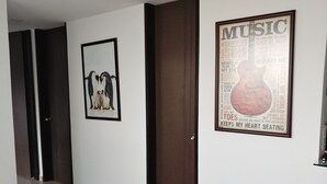 Ein Korridor mit einem gerahmten Bild von Pinguinen, einem gerahmten Musikplakat und einer geschlossenen Tür.