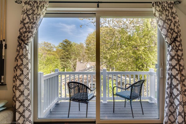 A balcony with two chairs and a white railing, overlooking a tree-lined area.