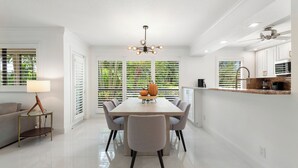 A modern kitchen with white cabinetry, a granite countertop, and a dining area with a table and chairs.