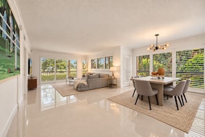 A spacious living area with a dining table and chairs, a sofa, and a television.