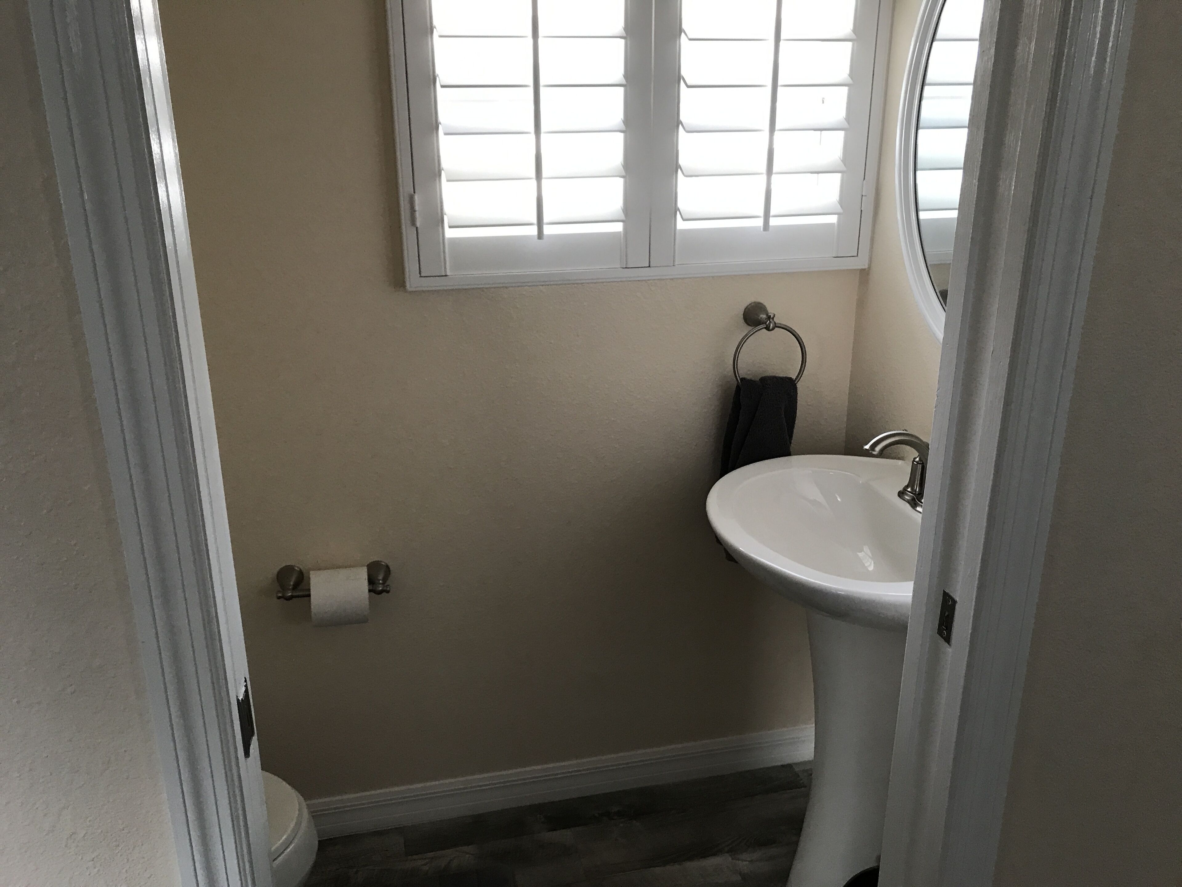 Un baño con inodoro, lavamanos y ventana con persianas.