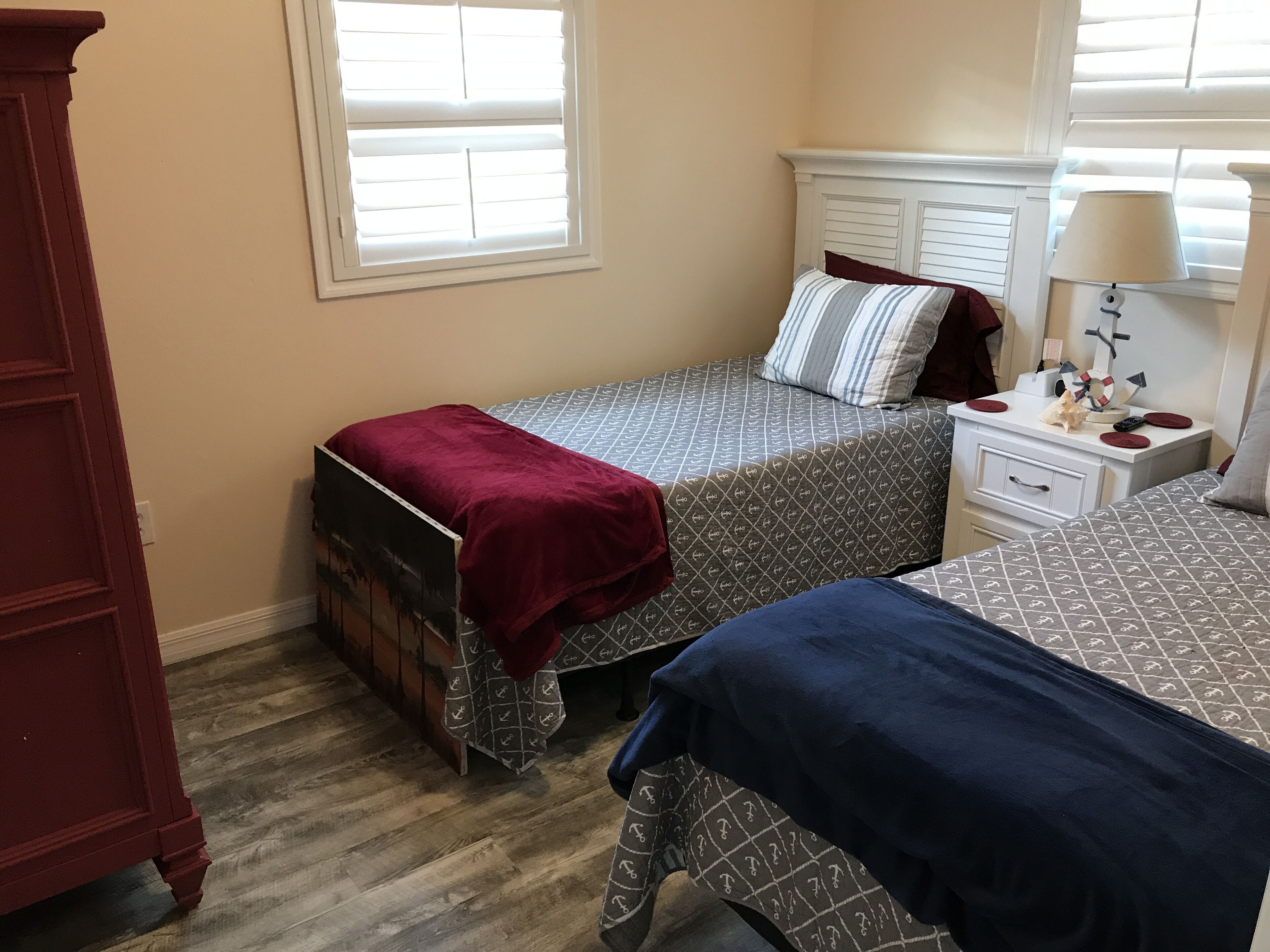 A bedroom with two beds, a dresser, a nightstand, and a lamp.
