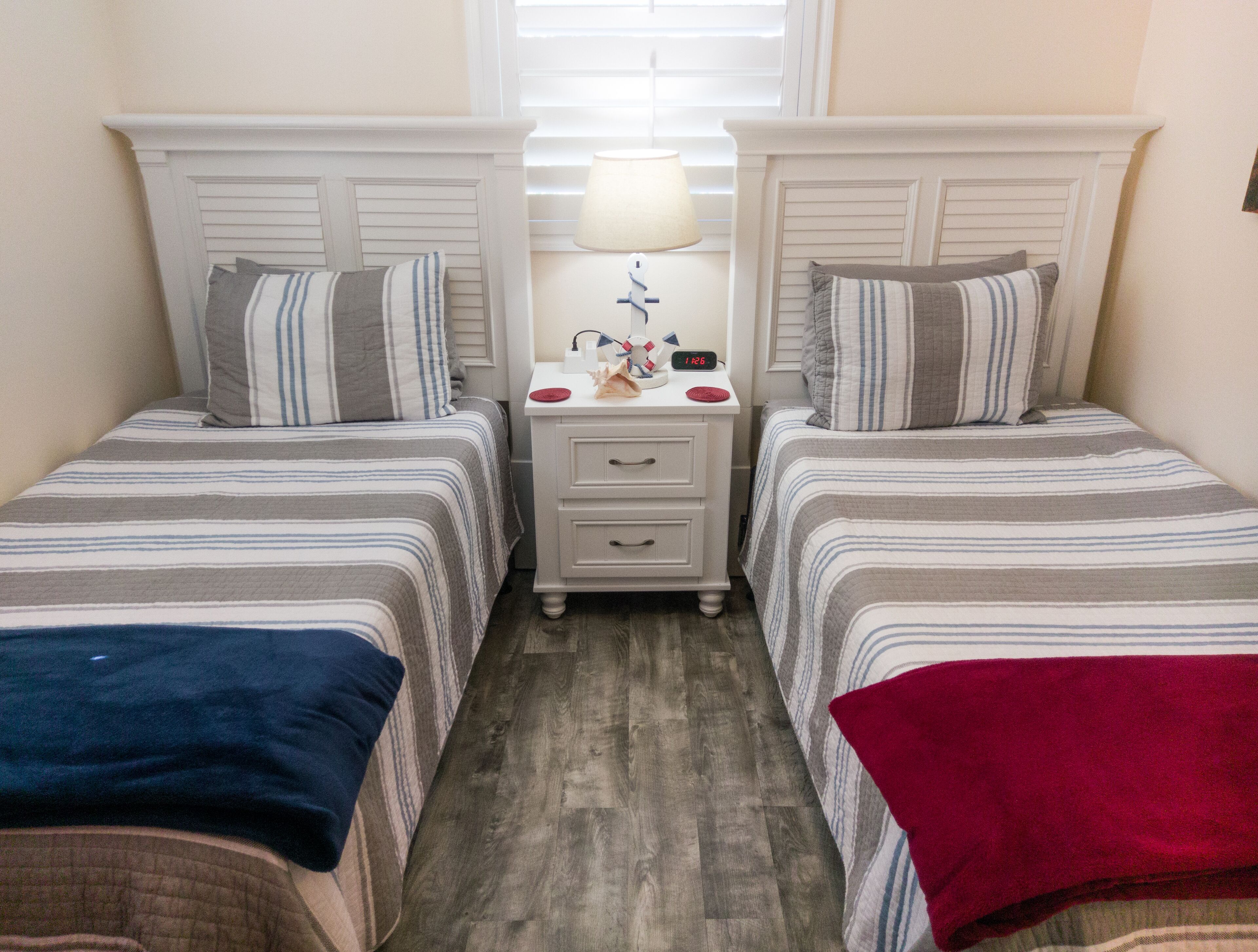 A twin room with two beds, a nightstand, a lamp, and a clock.