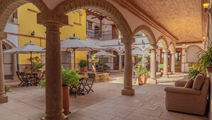 Un patio amplio con columnas de piedra, asientos al aire libre y plantas en macetas.