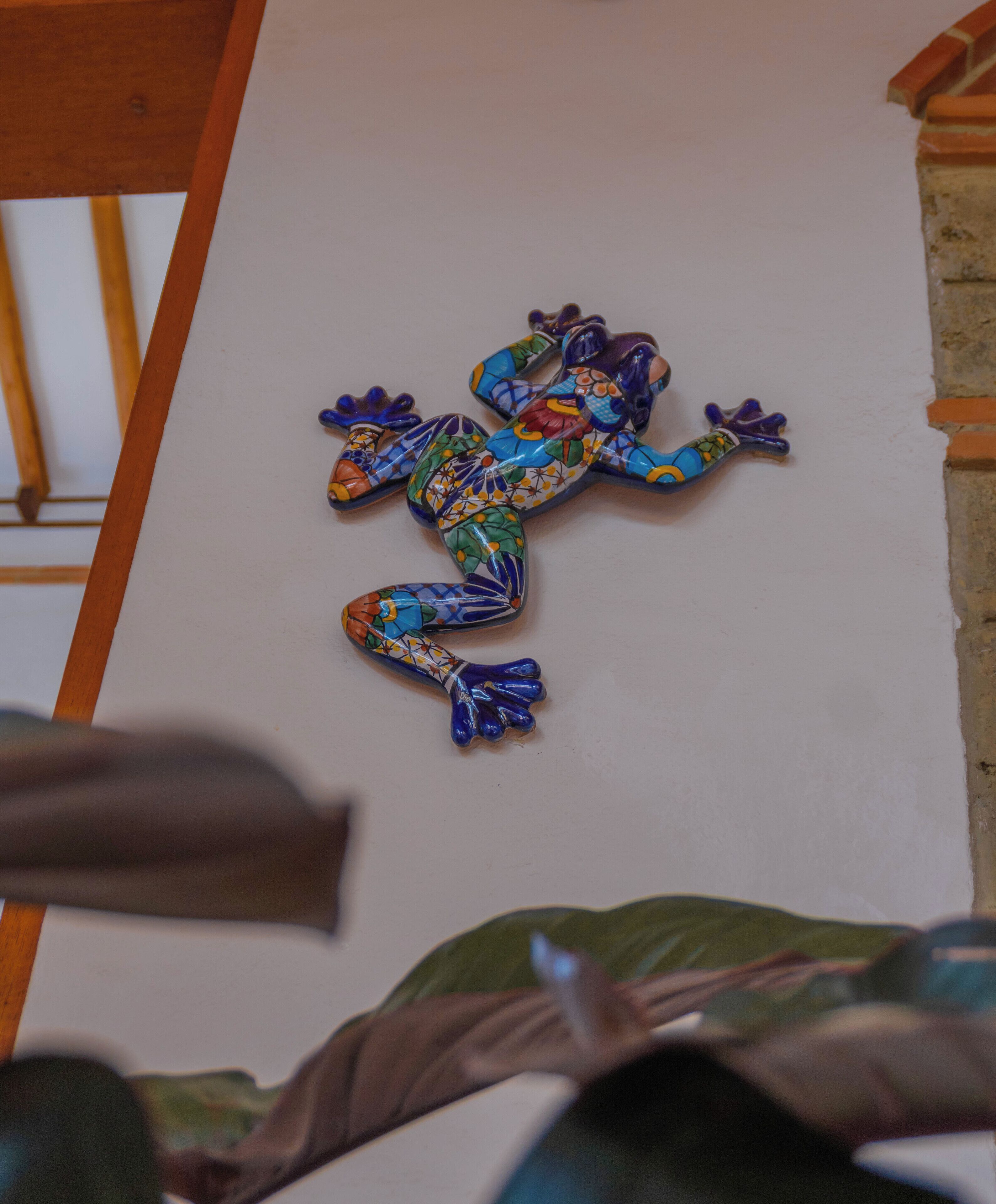 Eine farbenfrohe Froschskulptur an einer weißen Wand.