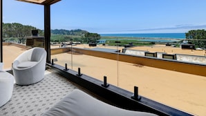 Quarto moderno com uma grande janela com vista para uma praia e o oceano.