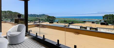 A modern room with a large window overlooking a beach and ocean.