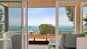 Varanda com vista para o mar, equipada com cadeiras e uma mesa.