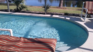 A swimming pool with a view of a lake, surrounded by a fence and a chair. - Exec. 4 Bedroom Home nr Disney,   Backs onto Conservation lands (Kissimmee)