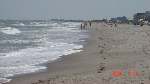 A beach with waves, people, and buildings in the background. - Exec. 4 Bedroom Home nr Disney,   Backs onto Conservation lands (Kissimmee)