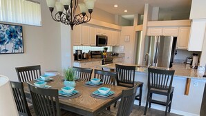 A dining area with a wooden table, dark chairs, and blue bowls. - Exec. 4 Bedroom Home nr Disney,   Backs onto Conservation lands (Kissimmee)