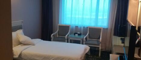 A hotel room with two beds, a desk, a chair, and a television.