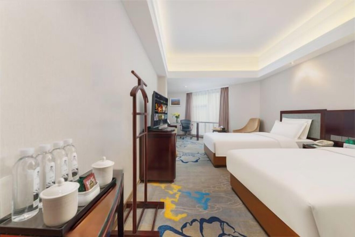 A hotel room with two beds, a desk with a computer, a chair, and a coffee station.